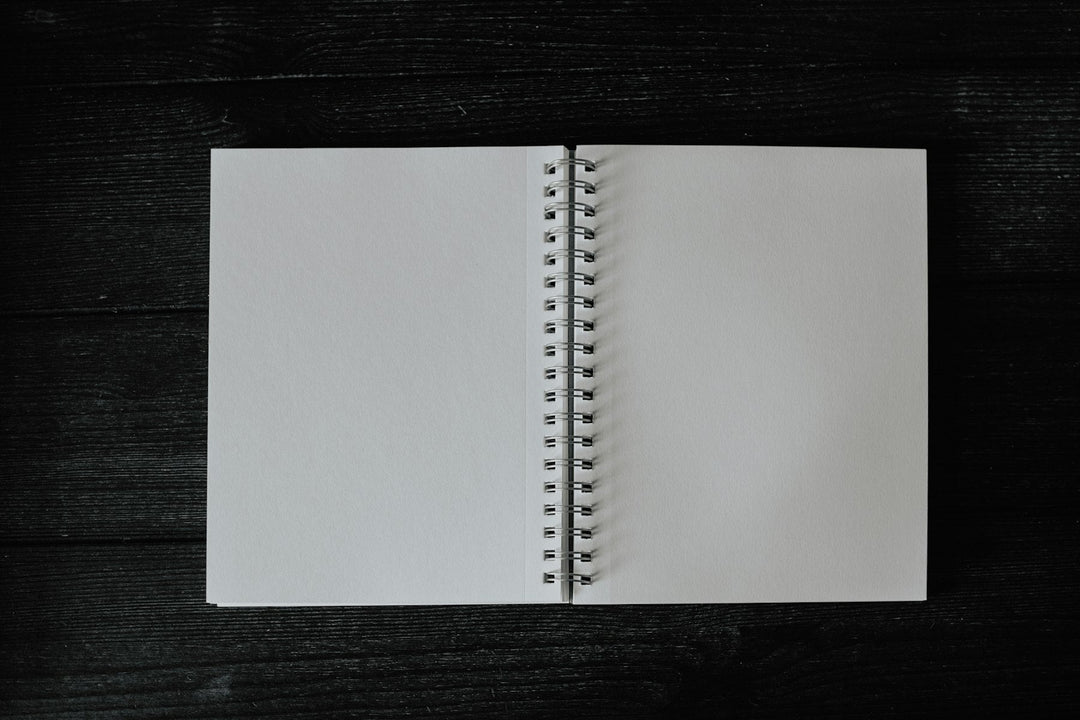 A blank open notebook on a dark wooden table