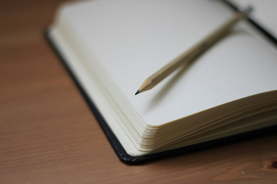 A wooden pencil resting on the pages of an open book in soft light