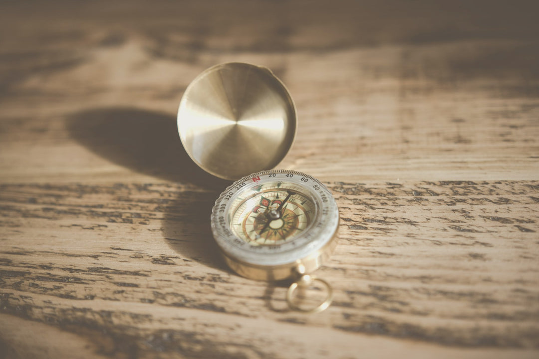 A brass compass resting on a weathered wooden surface