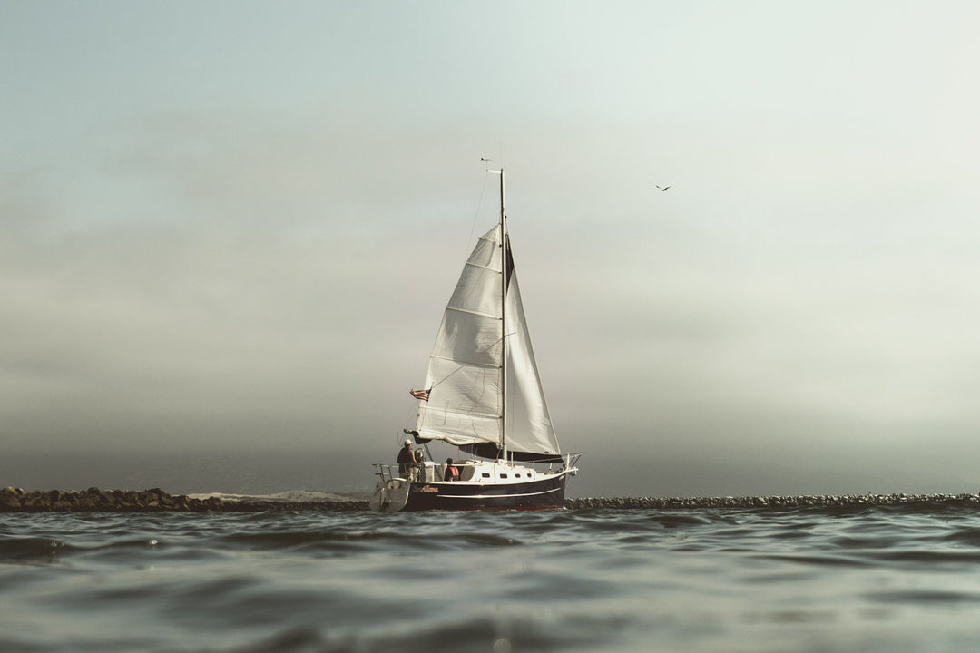A sailboat on open water under a pale sky