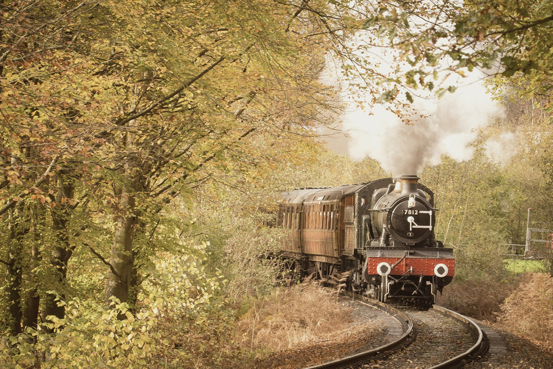A vintage steam train curving through autumn trees