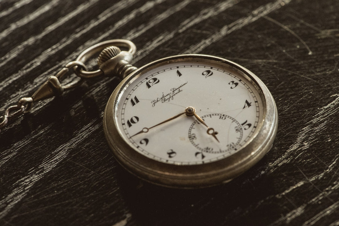 An open pocket watch on dark wood