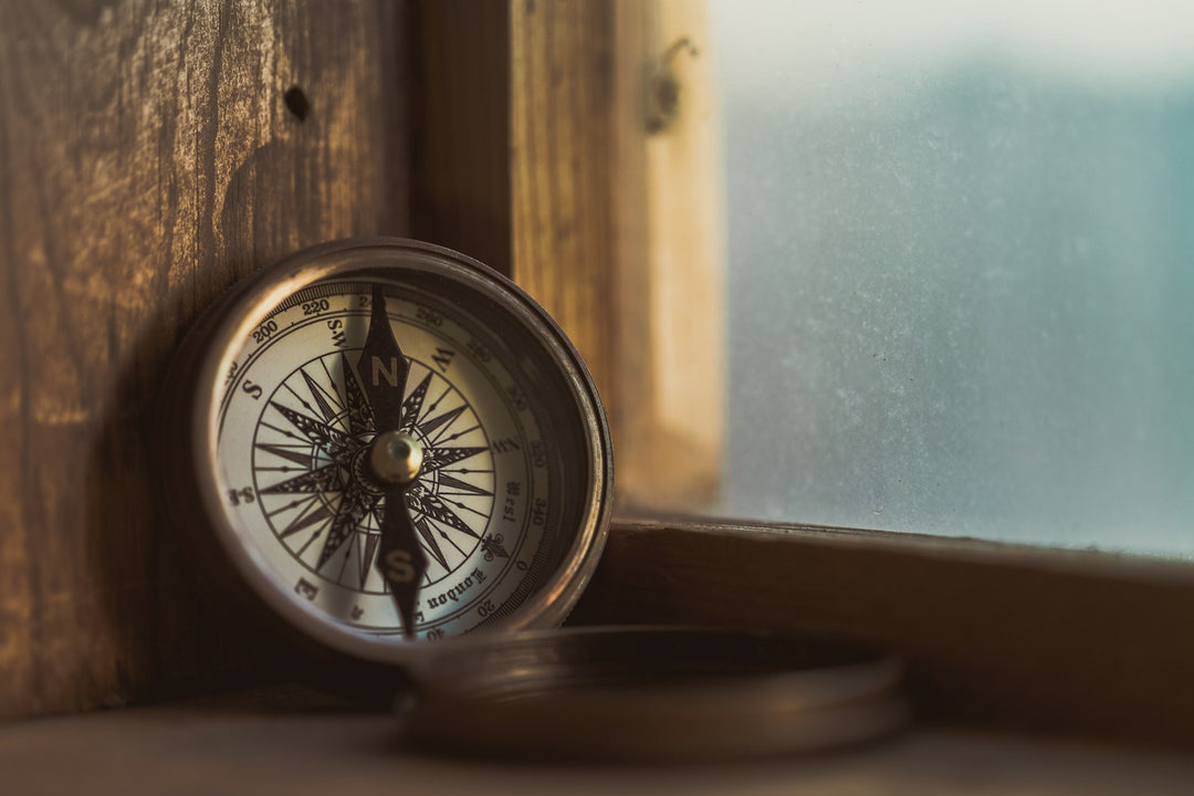 An antique compass on a windowsill