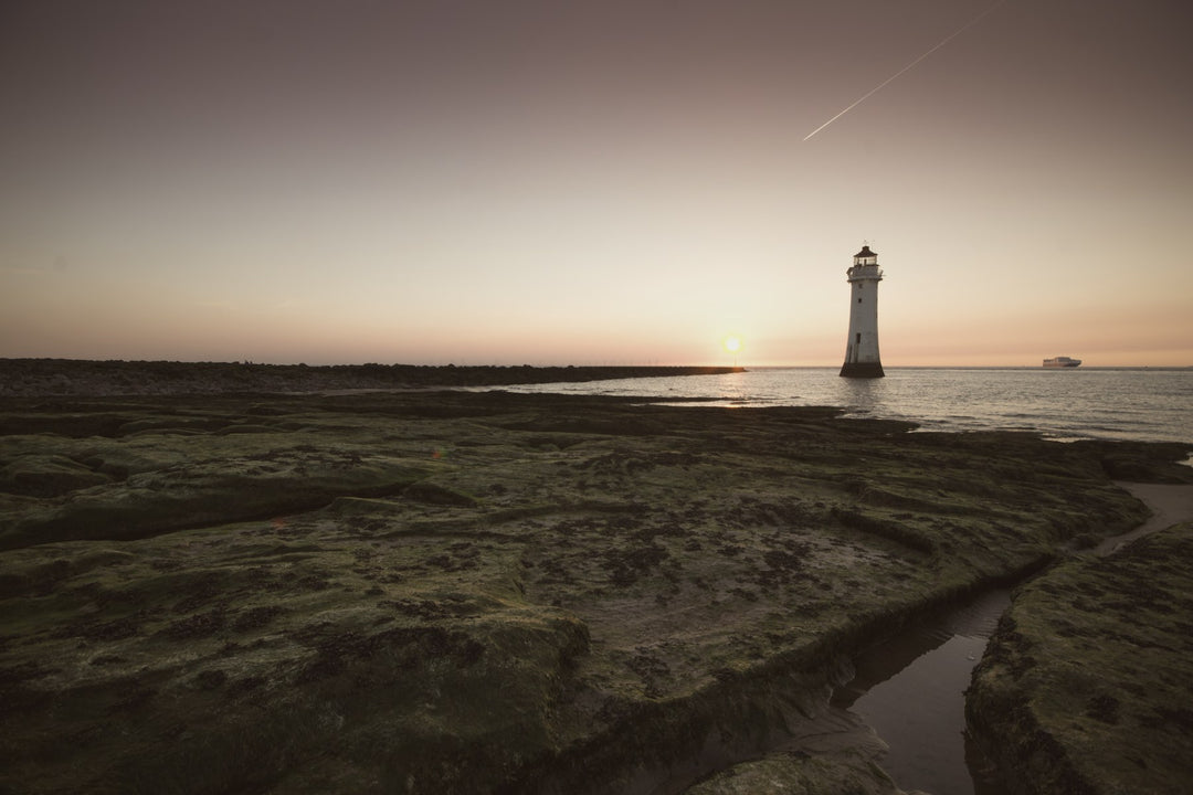 A distant lighthouse at dusk across a coastal marsh