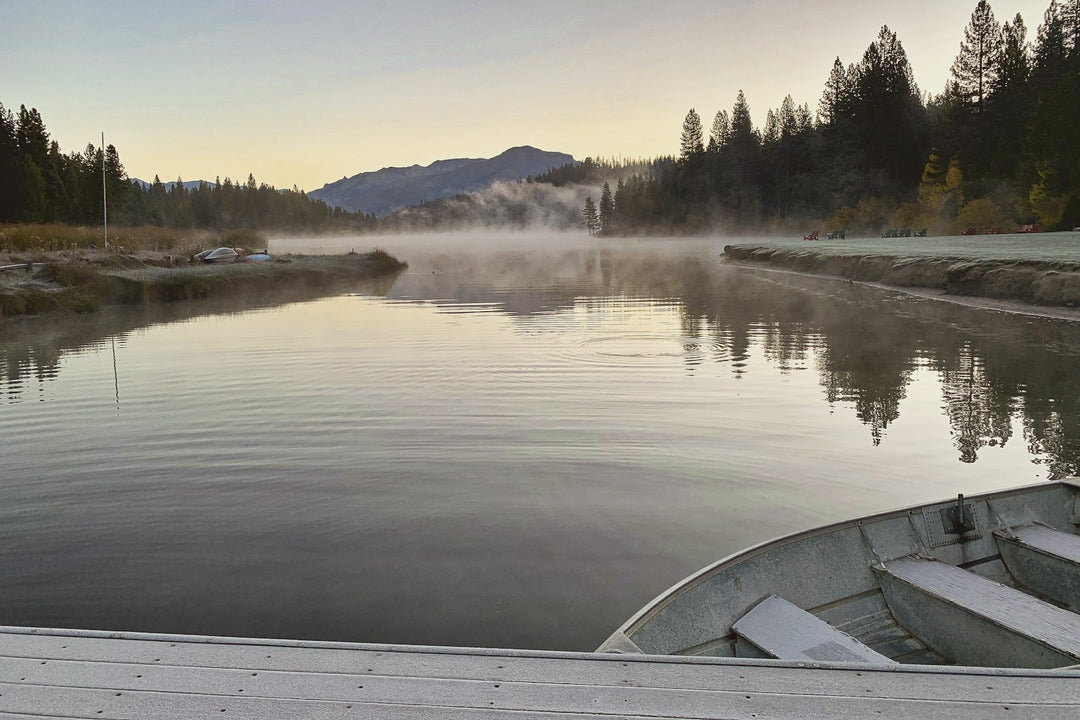 A mountain lake at sunrise seen from the bow of a small boat