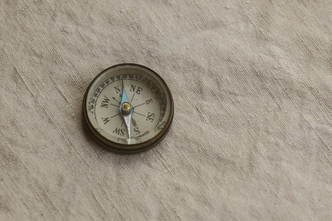 A small compass lying on textured paper