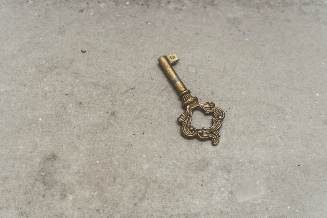 An antique brass key on a stone surface