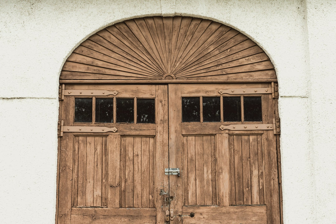An arched wooden door in a whitewashed wall