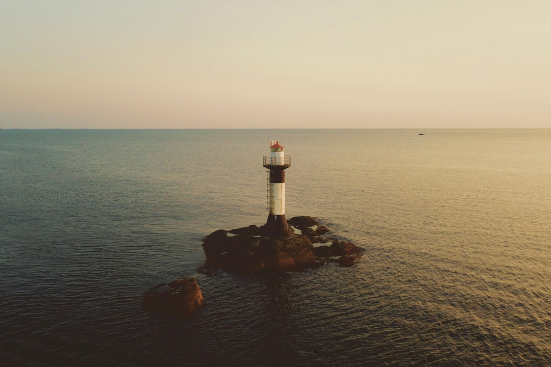 A small lighthouse on a rock at dusk over a calm sea