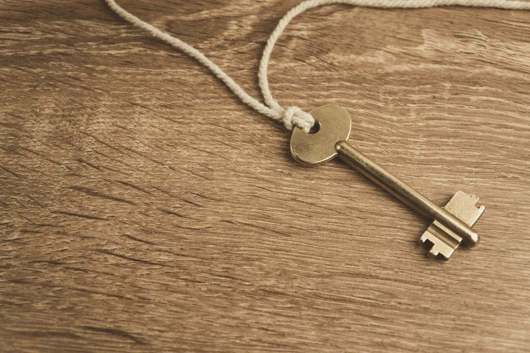 An old brass key tied with string on a wooden table