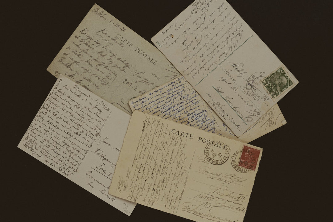 Old handwritten postcards scattered on a dark surface