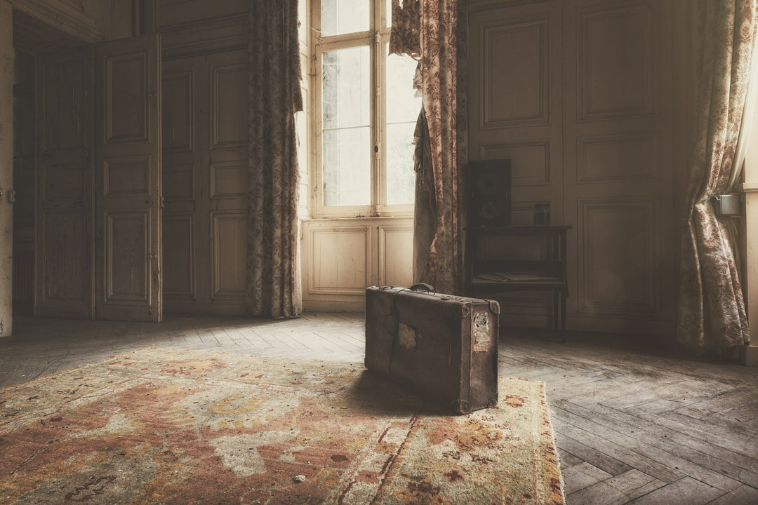 A lone vintage suitcase in a sunlit empty room