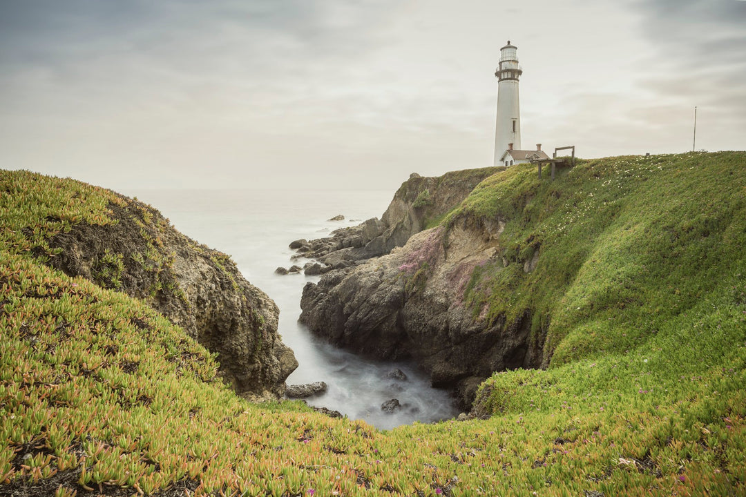 A lighthouse on a green clifftop above the sea