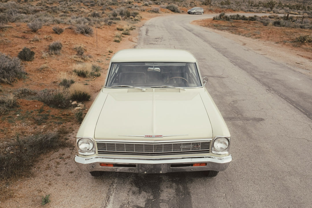 A classic cream car on a dusty country road