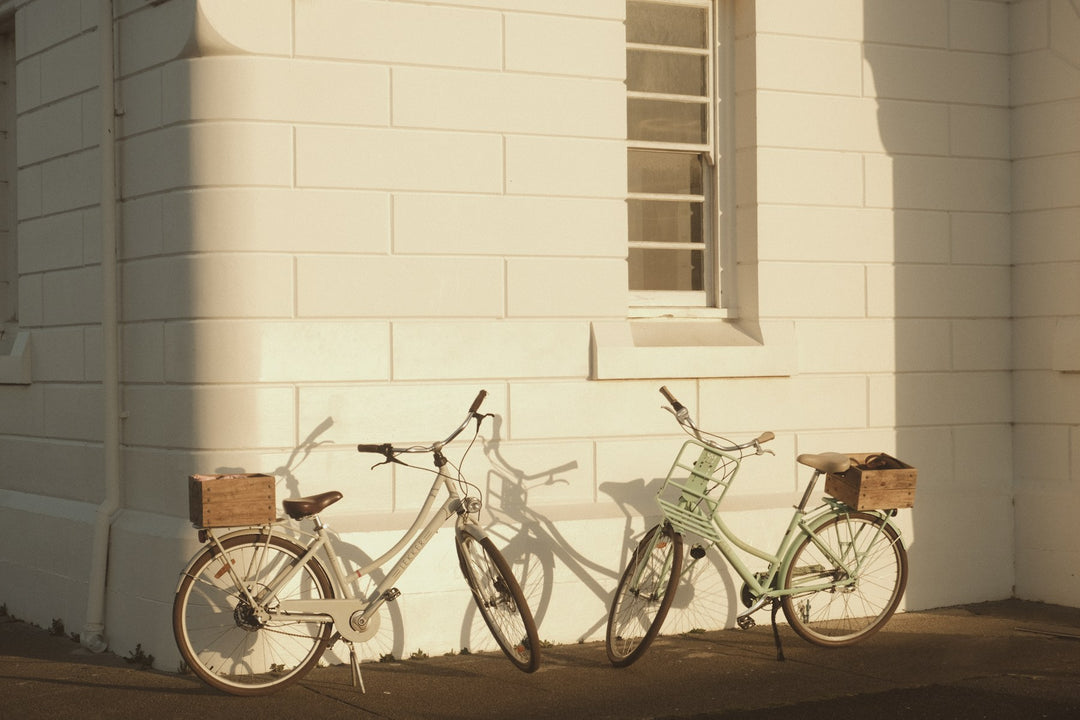Two vintage bicycles leaning against a sunlit wall
